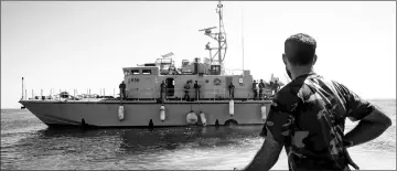  ??  ?? A Libyan coastguard looks towards a ship as he patrols the area at sea between Sabratha and Zawiyah. — AFP photo