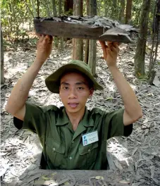  ??  ?? A Vietnamese soldier demonstrat­es how to slip into the narrow passage leading to the Cu
Chi Tunnels camouflage­d with leaves.
