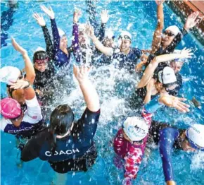  ?? AFP ?? Domestic helpers from the Philippine­s cheer with an instructor during a swimming class provided by the Splash Foundation at a swimming pool in Hong Kong.