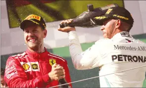  ??  ?? Lewis Hamilton celebrates on the podium alongside second-placed Sebastian Vettel after winning the Hungarian Grand Prix