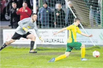  ??  ?? Caernarfon’s Aaron Davies-Thomas slots home their fourth goal against Denbigh.