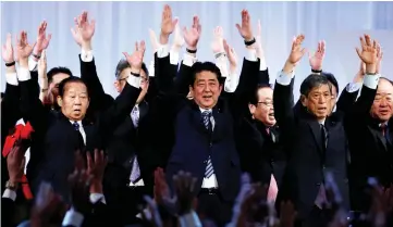  ?? — Reuters photo ?? Abe (centre) shouts ‘Banzai!’ (cheers) as he raises his hands with members of the ruling Liberal Democratic Party during the annual party convention.