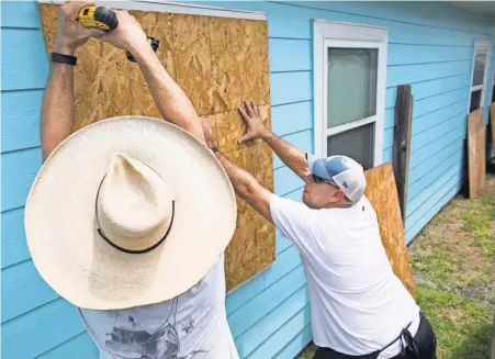  ?? COURTNEY SACCO, THE CALLER TIMES, VIA USA TODAY NETWORK ?? Jeff Moss and Kris Jones prepare for high winds and possibly days of flooding on Lighthouse Channel in Corpus Christi, Texas. Hurricane Harvey is forecast to hit Texas as a Category 3 storm.