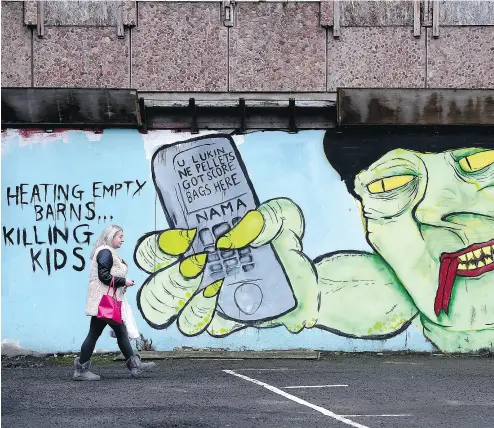  ?? CHARLES MCQUILLAN / GETTY IMAGES ?? A woman walks past a mural depicting DUP leader and Northern Ireland First Minister Arlene Foster, lampooning the country’s “cash for ash” policy fiasco. Foster now admits the scheme was badly botched.