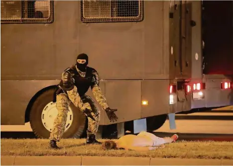  ?? (VASILY FEDOSENKO/REUTERS) ?? Un agent des forces antiémeute­s gesticule à côté d’une victime des affronteme­nts qui avaient suivi la fermeture des bureaux de vote à Minsk.