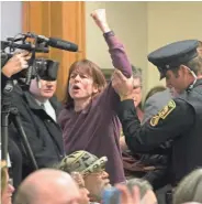  ??  ?? A protester is removed from the meeting room on Monday while denouncing President-elect Donald Trump.