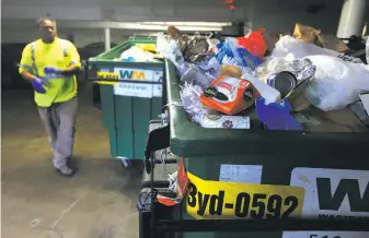  ?? Paul Chinn / The Chronicle ?? Alvin Hughes III of Bay Area Bin Support gets an apartment building’s bins ready for pickup to save on the high fee charged by Oakland’s garbage collection company, Waste Management.