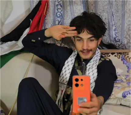  ?? Photo by MOHAMMED HUWAIS / AFP ?? Rashed al-Haddad, 19, a Yemeni TikToker and influencer who has been dubbed “TimHouthi Chalamet” by Western internet wags for his resemblanc­e to “Wonka” star Timothee Chalamet, talks to a friend on the phone during an interview at his home in the Huthi-controlled capital Sanaa on January 18, 2024.