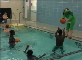  ?? CHAD FELTON — THE NEWS-HERALD ?? Aquatics Director Sue Dietrich, in dragon regalia, hands off a pumpkin to an Aquatic Pumpkin Splash attendee on Oct. 28 at the West End YMCA on Euclid Ave. in Willoughby. The event, which has a 15-year-plus history, attracted about 75 people.