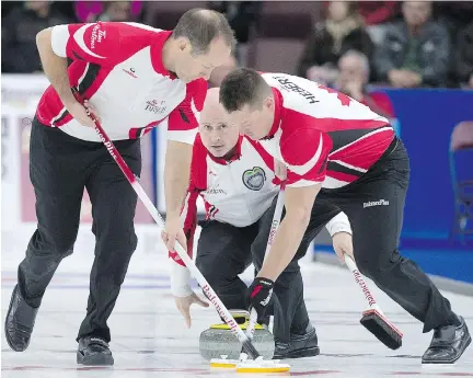 ?? ANDREW VAUGHAN/THE CANADIAN PRESS ?? Team Canada skip Kevin Koe watches his rock as Brent Laing, left, and Ben Hebert sweep against Manitoba at the Brier in St. John’s, Thursday. Koe’s rink won the match 6-3 before losing 7-6 to Brad Gushue, the hometown favourite, in the late draw.