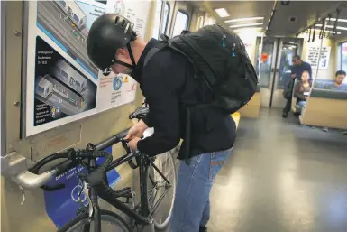  ?? Photos by Paul Chinn / The Chronicle ?? Michael Floyd anchors his bike with straps installed on a BART train at the El Cerrito del Norte station.