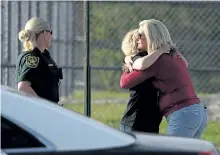  ?? JOE RAEDLE/GETTY IMAGES ?? Assistant principle Denise Reed, right, hugs a school employee as she arrives at Marjory Stoneman Douglas High School in Parkland, Fla., on Friday.