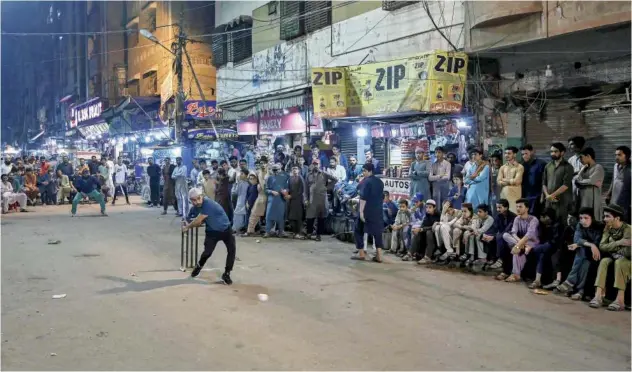  ?? Agence France-presse ?? ↑
A youngster plays night cricket match as spectators watch during Ramadan in Karachi on Wednesday.