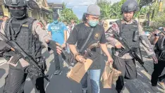  ??  ?? TRACES OF TERROR: Policemen carry envelopes after a raid at the house of Nur Rohman, a friend of Bahrun Naim, who blew himself up at a Solo police station in July.