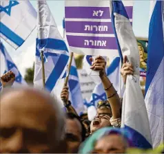  ?? OHAD ZWIGENBERG /ASSOCIATED PRESS ?? Israelis wave national flags and banners Monday outside Israel’s parliament in Jerusalem during a protest against plans by Prime Minister Benjamin Netanyahu’s new government to overhaul the judicial system and gut the power of judges.