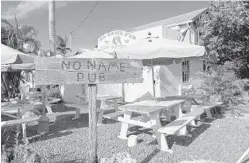  ??  ?? Above left: No Name Pub after Hurricane Irma on Sept. 13, 2017. Hurricane Irma caused extensive damage to the kitchen equipment and the rear outside dining area, but spared the original wood bar and thousands of dollar bills left by visitors hanging inside the famous pub. Above right: The revived pub on No Name Key.