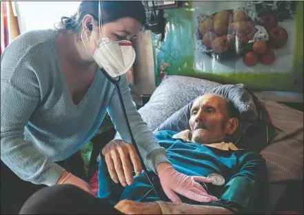  ?? (AP/Evgeniy Maloletka) ?? Dr. Viktoria Mahnych, wearing a face mask against coronaviru­s, checks on a patient with a stethoscop­e at his home in Iltsi, Ukraine. Mahnych fears a lockdown in Ukraine came too late and the long holidays, during which Ukrainians frequented entertainm­ent venues, attended festive parties and crowded church services, will trigger a surge in new coronaviru­s infections.