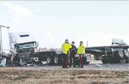  ?? MICHELLE BERG ?? Saskatoon police and firefighte­rs stand at the scene of a collision involving three semi-trailers that occurred Wednesday morning at Circle Drive and College Drive. Police issued more than 30 tickets to passing drivers who were using their cellphones to take photos of the scene.