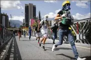  ?? CUBILLOS / ASSOCIATED PRESS ?? Anti-government demonstrat­ors take cover from Venezuelan national guardsmen at a protest against President Nicolas Maduro in Caracas on Saturday.