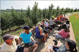  ?? CURTIS COMPTON/CCOMPTON@AJC.COM ?? Visitors get a tour from a wagon pulled by a tractor on their way to the orchards.