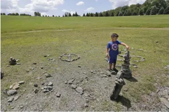  ?? AP ?? TIMES CHANGE: Caleb Hairston, 4, last month leaves flowers he picked where the stage was for the 1969 Woodstock Music and Arts Fair in Bethel, N.Y. The celebratio­n marking the 50th anniversar­y won’t be the free-for-all the original became, where fans got wild, below, and performers, including Richie Havens, left, played before a crowd of about 400,000.