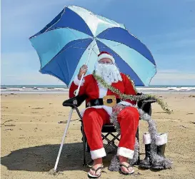  ?? ROBYN EDIE / STUFF ?? Santa Claus enjoys the heat at Southland’s Oreti Beach this weekend.