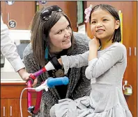  ?? NWA Democrat-Gazette/DAVID GOTTSCHALK ?? Julie Marvin watches as her daughter Gracie, a first-grader at Willis D. Shaw Elementary School, places her arm in the new prosthetic attached to the handlebars of her bicycle Tuesday at the school in Springdale.