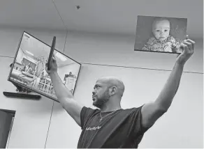  ?? JORDAN LAIRD/COLUMBUS DISPATCH ?? Jontue Chatman holds up photos of his infant son, Kashan Roman Crawford-chatman, on Wednesday in Franklin County Common Pleas Court at the arraignmen­t of Tammra Straughter, a Reynoldsbu­rg home daycare operator whom the prosecutor’s office has accused of shaking 5-month-old Kashan, causing his death in October 2023.