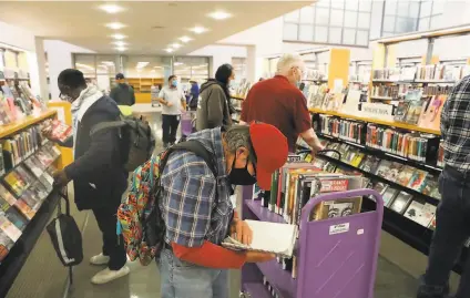  ?? Lea Suzuki / The Chronicle ?? Patrons browse at San Francisco’s Main Library after it reopened last month. Most library branches remain closed.