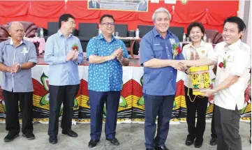  ??  ?? Superinten­dent of Land and Survey Kapit JawanTumba (right) presents a souvenir to Awang Tengah after the event.