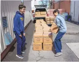  ?? ?? Annunciati­on Catholic School eighth graders Jacob Osborne, left, and Jacob Roberts stack boxes full of packaged food during the Hands of Hope project at Annunciati­on Catholic School on Wednesday.
