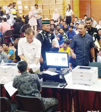  ??  ?? Director-General of Immigratio­n Datuk Seri Mustafar Ali observing the E-Kad registrati­on at the Immigratio­n Department head office yesterday.