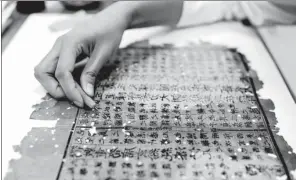  ?? MAI TIAN AND WENG XINYANG / FOR CHINA DAILY ?? Top: A woman selects paper before starting to mend ancient books at a special facility in Hangzhou, Zhejiang province. Above: A damaged ancient document is restored at the National Library of China.