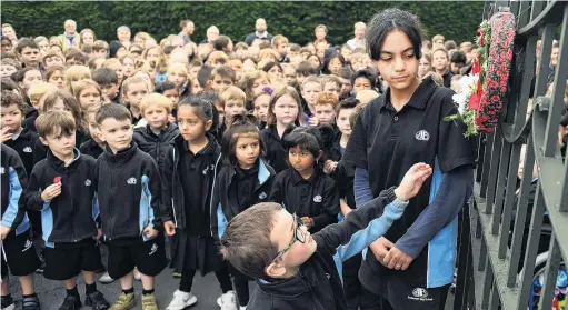 ?? PHOTO: STEPHEN JAQUIERY ?? With respect . . . Anderson’s Bay School pupils Sidney Austin (5) and Joulia Dibo (10) place a wreath on the school’s memorial gates during their Anzac service yesterday.
