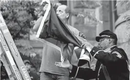  ?? KAREEM ELGAZZAR/CINCINNATI ENQUIRER ?? Reginald Murray hands over the Juneteenth Flag to be raised Friday at City Hall in Cincinnati. Juneteenth is a now a national holiday.