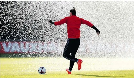  ??  ?? Teures Nass: Vor dem Spiel gegen Österreich wurde Gareth Bale von einem Rasenspren­ger überrascht. Dabei wurden fast 100 Millionen Euro nass, so teuer war der Superstar von Wales im Jahr 2013