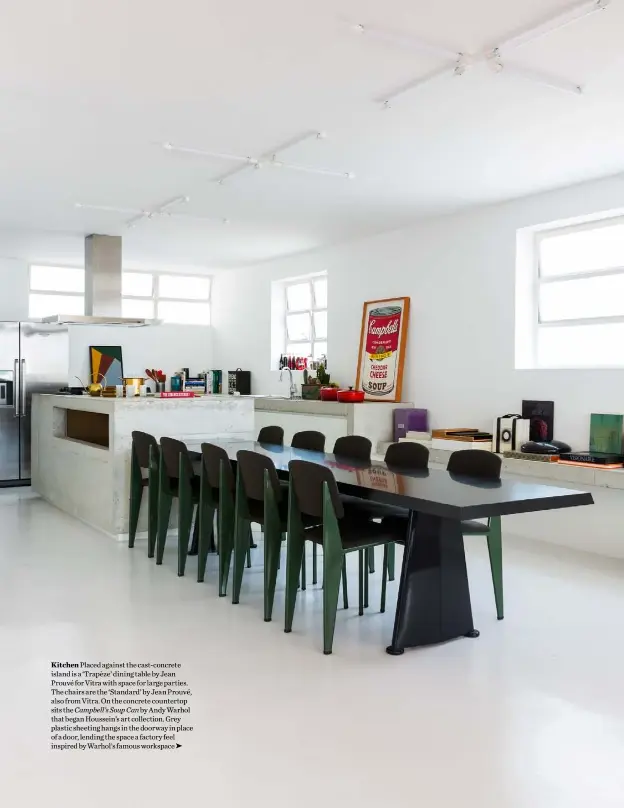  ??  ?? Kitchen Placed against the cast-concrete island is a ‘Trapèze’ dining table by Jean Prouvé for Vitra with space for large parties. The chairs are the ‘Standard’ by Jean Prouvé, also from Vitra. On the concrete countertop sits the Campbell’s Soup Can by Andy Warhol that began Houssein’s art collection. Grey plastic sheeting hangs in the doorway in place of a door, lending the space a factory feel inspired by Warhol’s famous workspace