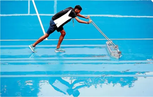  ?? GETTY IMAGES ?? A ballboy sweeps the court as rain falls during day one of the ASB Women’s Classic at ASB Tennis Centre in Auckland yesterday.