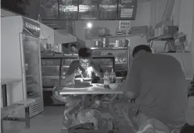  ?? OLIVIA ZHANG/AP ?? Breakfast is eaten by the light of a smartphone Wednesday during a blackout in Shenyang in northeaste­rn China’s Liaoning Province.