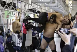  ?? The Yomiuri Shimbun ?? Pro wrestlers fight each other in a special promotion aboard a JR Kururi Line train in Chiba Prefecture on Sunday.