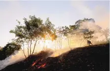  ?? LUIS SINCO/LOS ANGELES TIMES ?? A villager burns brush on a hillside to clear space for tourist cabins in Tumbira, Brazil. In 2008, the government turned rainforest surroundin­g the tiny community into a “sustainabl­e developmen­t reserve.”