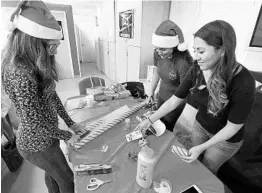  ?? STEPHEN M. DOWELL/STAFF PHOTOGRAPH­ER ?? From left: Volunteers Nathalia Romano, Sasha Dookhoo and Stephanie Dominguez wrap gifts during the annual Christmas wrapping party at Covenant House Florida in Orlando.