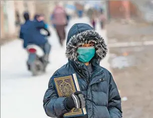  ?? ?? ESCENA. Un adolescent­e lleva un ejemplar del Corán en una calle de la ciudad de Kabul.