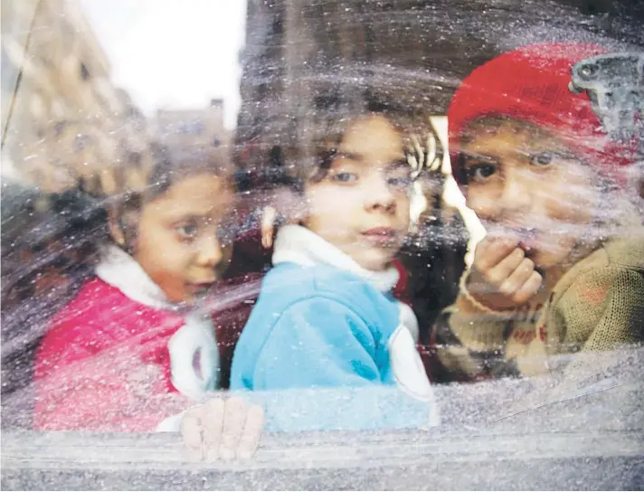  ??  ?? ► Niños miran por la ventana de un bus durante la evacuación desde la asediada ciudad de Douma, en Guta Oriental, el martes.