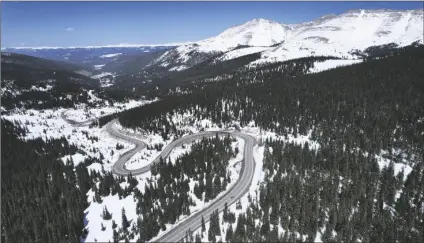  ?? BRITTANY PETERSON/AP ?? A ROAD WINDS THROUGH the snow-covered Rocky Mountains at Hoosier Pass as seen from the air, April 18, near Blue River, Colo.