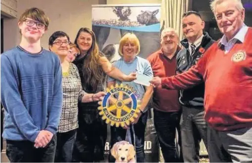  ??  ?? Barking up the right tree Fiona MacDonald (centre, left) and support dog Maggie (front) gratefully accept the Rotarians’ £200 donation