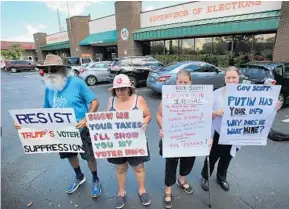  ?? JOE BURBANK/STAFF PHOTOGRAPH­ER ?? Left to right, Gary Mogensen, Barbara Ventarola, Carrie Barker-Carson and Karen Louden hold signs on Monday protesting President Donald Trump’s demand for voter informatio­n.