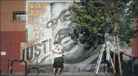  ?? Jason Armond Los Angeles Times ?? TRISTAN EATON paints his Malcolm X mural onto the coffee shop Café de Leche Tuesday in Highland Park. Eaton is a nationally renowned street artist.