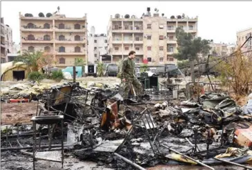  ?? GEORGE OURFALIAN/AFP ?? A Russian soldier inspects the damage at a field hospital that was reportedly destroyed by rebel shelling on Monday in the Furqan neighbourh­ood of the government-held side of west Aleppo.