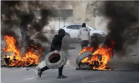  ?? Photograph: Ahmad Gharabli/AFP/Getty Images ?? Palestinia­n protesters burn tyres to block a road leading into Jericho after the raid by Israeli forces.